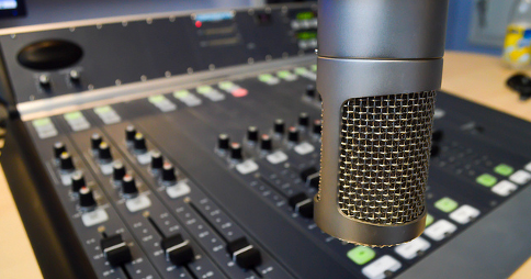 Microphone in front of an audio mixing console. Image credit: marvinjvds via Flickr